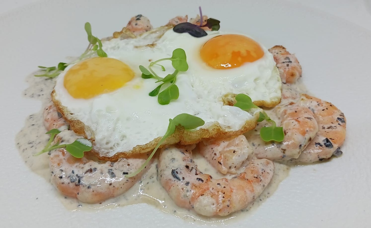 Cremoso revuelto de langostinos de Sanlúcar, realzado con delicada salsa de trufa y huevos de corral frescos.